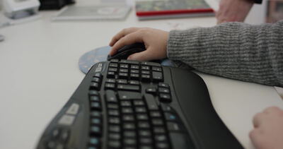 Hände tippen auf ergonomischer Tastatur und Maus am Schreibtisch Hände tippen auf ergonomischer Tastatur und Maus am Schreibtisch, Hände tippen Tastatur, ergonomische Tastatur und Computer