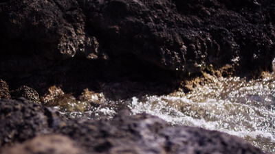 Schäumendes Wasser fließt in Nahaufnahme über dunkle nasse Felsen