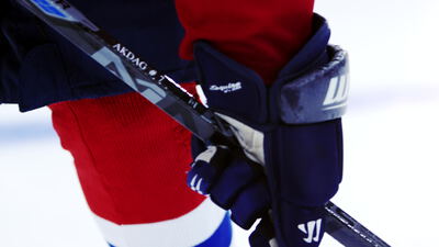 Eishockeyspieler hält Schläger mit gepolsterten Handschuhen