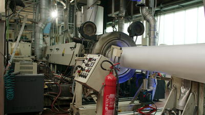 Kunststoffrohr verlässt den Kalibrierkopf der Extrusionslinie