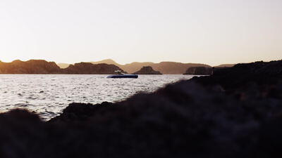 Motoryacht gleitet in der blauen Dämmerung an der Felsküste entlang