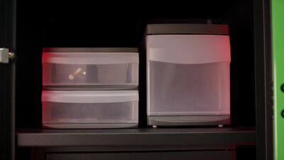 Transparente Kunststoffboxen mit Tabletten im Medikamentenschrank