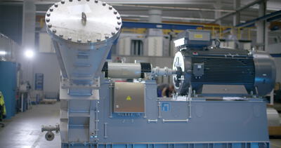 Große Industriemaschine mit Trichter und Elektromotor in einer Fabrikhalle