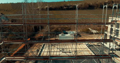 Baugerüst um einen Neubau im Rohbau am Feldrand aus der Luft