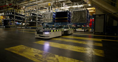 Autonomer Transportroboter fährt über markierte Sicherheitsstreifen in der Fabrik