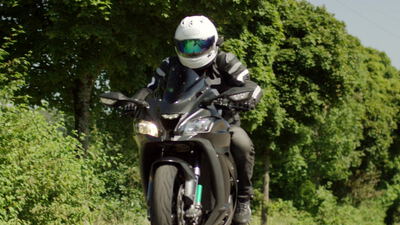 Motorradfahrer auf einem schwarzen Sportmotorrad auf der Landstraße