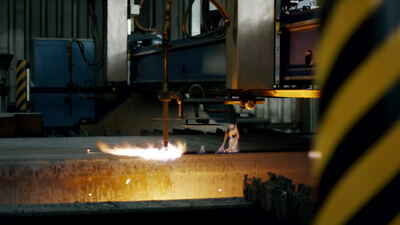 Flamme bearbeitet ein glühendes Metallstück mit Funken im Stahlwerk