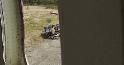 Blick aus einer Flugzeugtür auf ausgebaute Flugzeugsitze im Freien