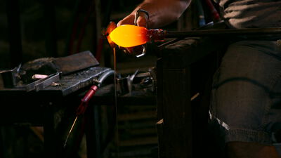 Glasbläser formt glühendes Glas mit dem Handwerkzeug
