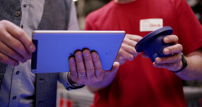 Zwei Personen prüfen ein blaues Kunststoffteil mit einem Tablet: Tablet Bauteilprüfung, blaues Kunststoffteil