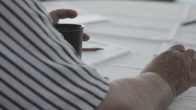 Hände am Tisch mit Kaffeetasse und Unterlagen im Gespräch