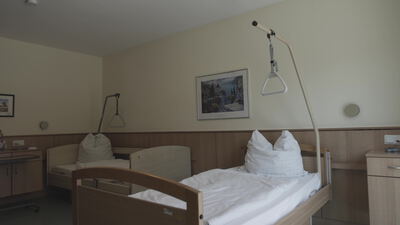 Pflegebett mit Bettgalgen in einem hellen Krankenzimmer
