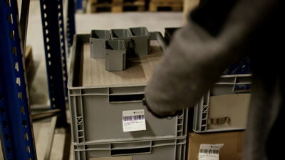 Lagerarbeiter scannt Barcode Etikett an einem Behälter im Lager