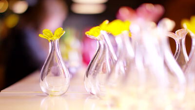 Kleine Glasvasen mit gelben Blüten auf einem Ladentisch