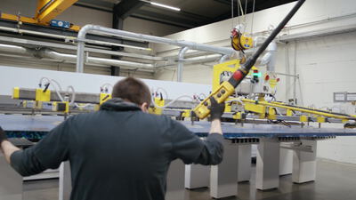 Arbeiter bedient Vakuumheber für große Platte in der Fabrik