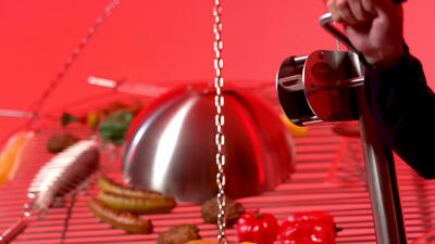 Chromhaube über einem Grillrost mit Würsten vor rotem Hintergrund, Grillhaube, Grillen und Bratwurst als 4K Stockvideo