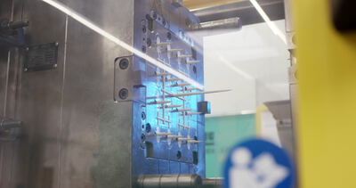 Detail einer Spritzgussform mit weißen Formteilen in Blau