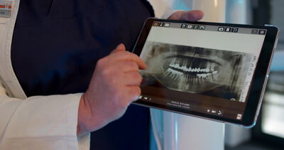 Zahnarzt zeigt Röntgenaufnahme des Gebisses auf einem Tablet