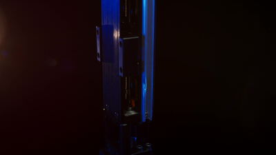 Schlankes metallisches Bauteil im blauen Licht vor dunklem Hintergrund