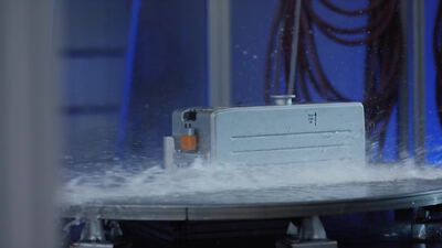 Wasserstrahl trifft elektronisches Steuergerät beim Spritzwassertest auf dem Prüfstand