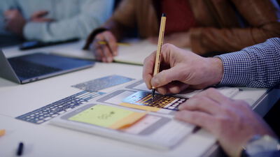 Hände schreiben mit Bleistift auf Entwürfen in einer Besprechung