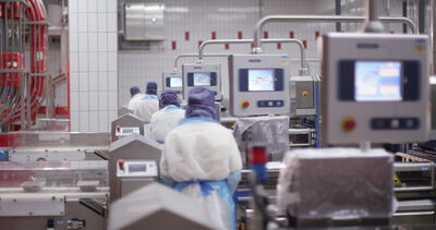 Arbeiter bedienen Verpackungsmaschinen in einer modernen Lebensmittelfabrik