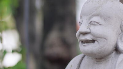 Lächelndes Gesicht einer steinernen Buddha Statue im Tempelgarten