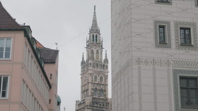 Gotischer Glockenturm ragt zwischen zwei Häuserfassaden empor
