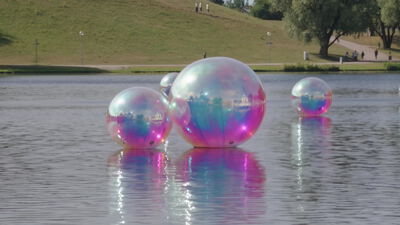 Große Wasserkugeln schimmern in Regenbogenfarben auf einem See: Wasserkugeln, Regenbogenfarben