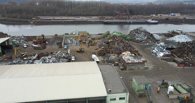 Schrottrecyclinghof am Fluss mit vielen Containern von oben
