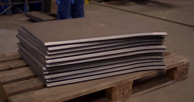 Stapel zugeschnittener Stahlplatten auf einer Holzpalette