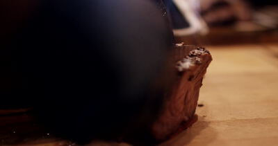 Behandschuhte Hände schneiden gegrilltes Fleisch auf dem Holzbrett