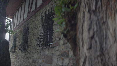 Altes Natursteinhaus mit schmiedeeisernem Fenstergitter im Regen