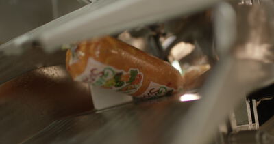 Verpackte Wurst gleitet über eine Edelstahlrutsche in der Fleischfabrik