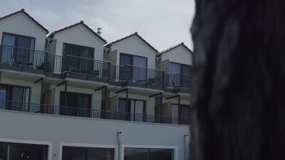 Modernes Mehrfamilienhaus mit Balkonen hinter einem Baumstamm