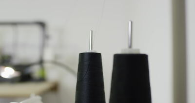 Schwarze Garnkonen versorgen die Industrienähmaschine mit Garn, schwarze Garnkone Nähmaschine, Nähgarn Kone Nahaufnahme und