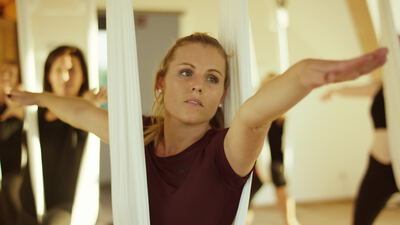 Frauen üben Yoga mit Tüchern in einem hellen Studio
