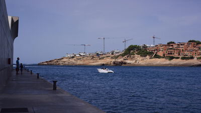 Küstenstadt mit Baukränen und belebter Uferpromenade