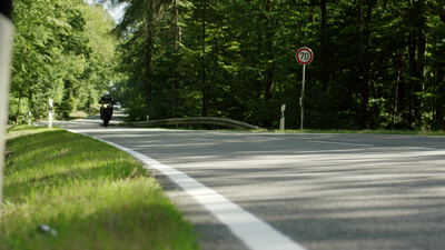 Motorrad fährt auf einer Landstraße mit Tempo 70 Schild