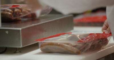 Verpackte Würste werden auf einer Edelstahlwaage im Betrieb gewogen