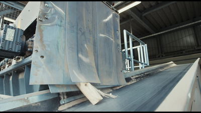 Nahaufnahme eines Förderbands mit Stahlabweiser beim Materialtransport