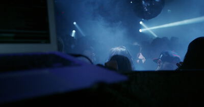 Menschenmenge feiert im Nachtclub zwischen Nebel und blauen Lichtstrahlen