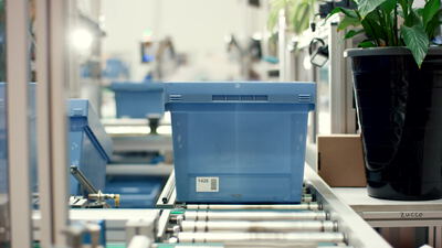 Blaue Transportbox auf dem Rollenförderer in der Produktion