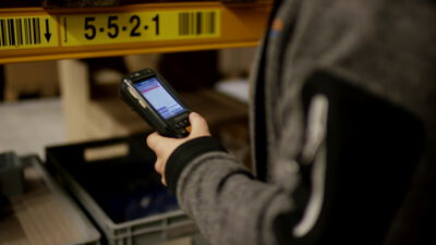 Lagerarbeiter scannt Barcode mit Handscanner am Regal