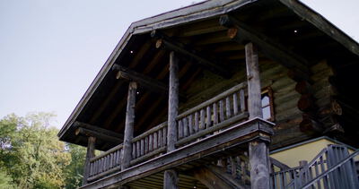Alte Holzhütte mit Balkon und Giebeldach im Wald