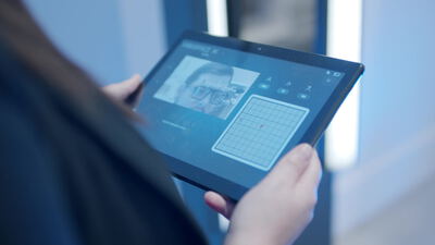 Hand hält Tablet mit digitalem Zahnscan in moderner Praxis