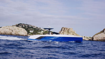 Sportyacht gleitet zwischen Felsinseln über blaues Wasser