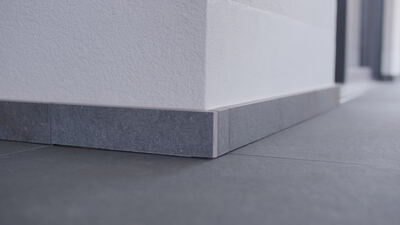 Weiße Fassade mit dunklem Steinsockel an einer Gebäudeecke