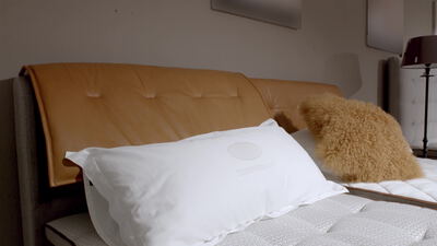 Weißes Kopfkissen an einem Lederkopfteil im gemütlichen Schlafzimmer