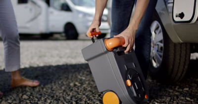 Person zieht einen Rollkoffer über den Parkplatz